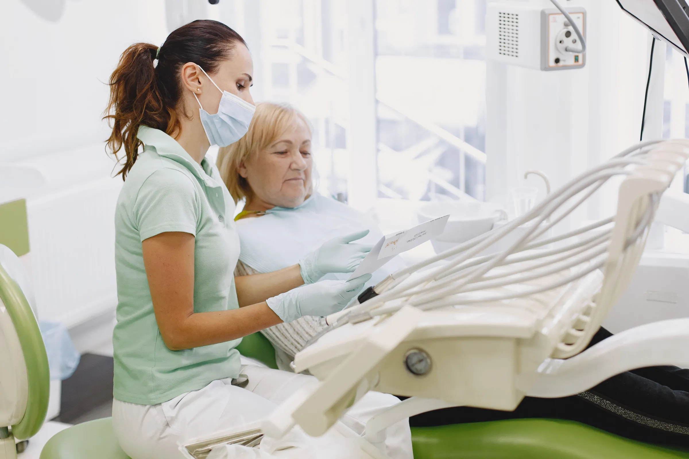 A clinician talks through a treatment plan with an older patient in the dental chair