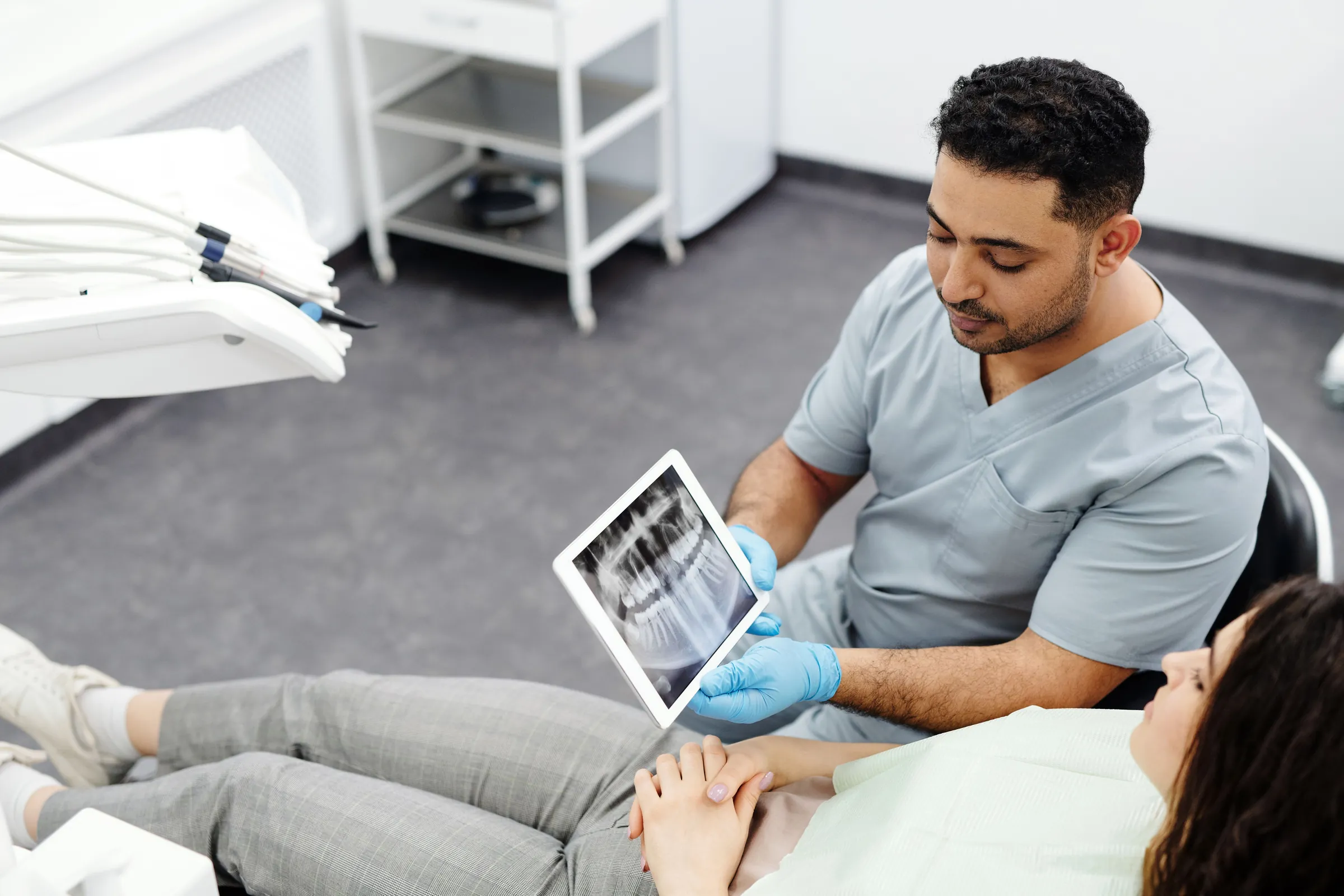 A surgeon reviews an X-ray on a tablet with a patient in a bright clinic
