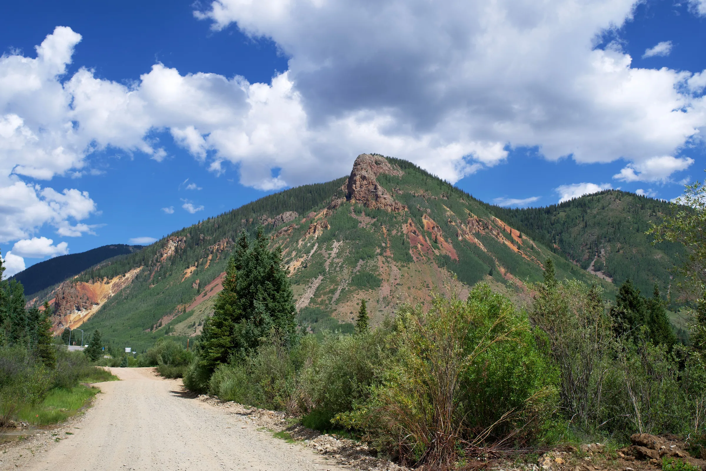 A gravel road toward a red-rock peak in the San Juan Mountains